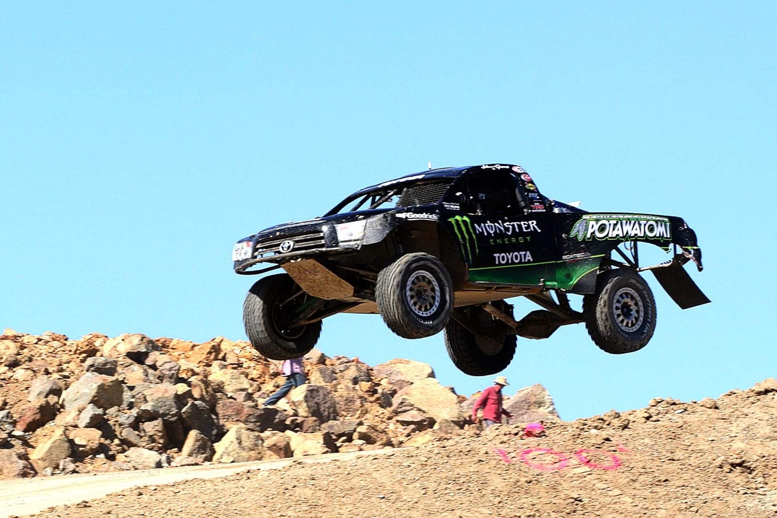 Monster truck na wielkich kołach pokonuje ziemny wał na torze przeszkód